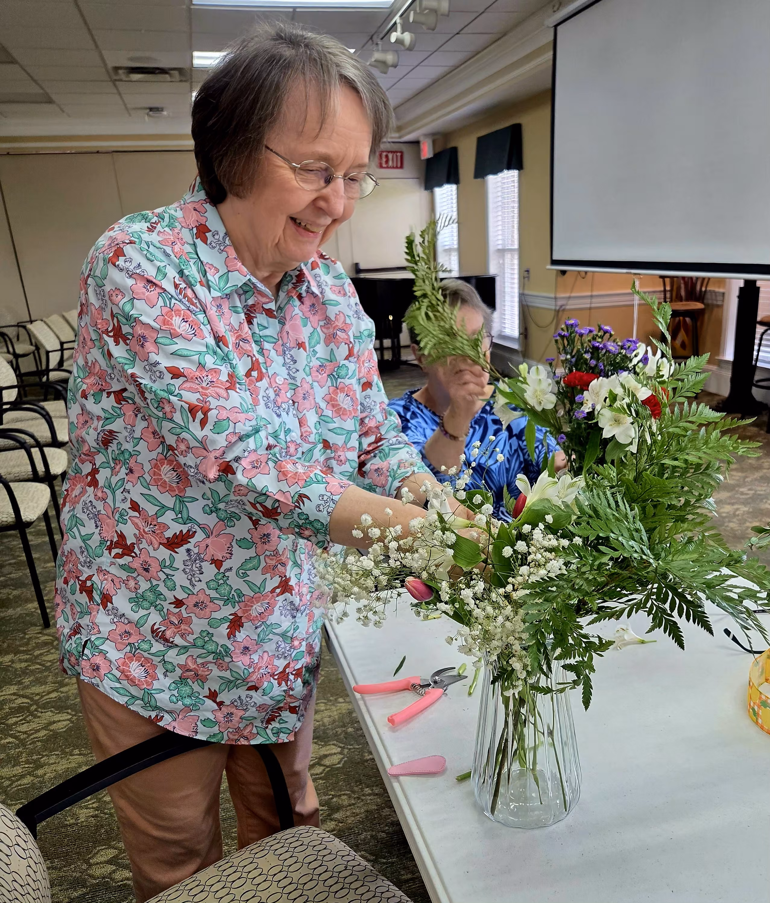 Image of a woman arranging flowers in a vase.