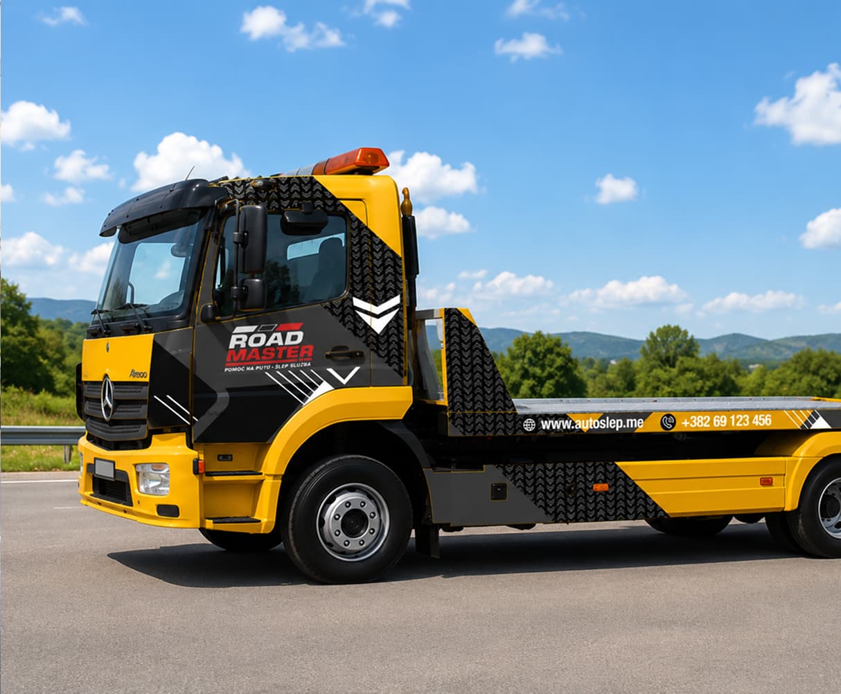 Yellow and black flatbed tow truck with Road Master branding on a sunny road.
