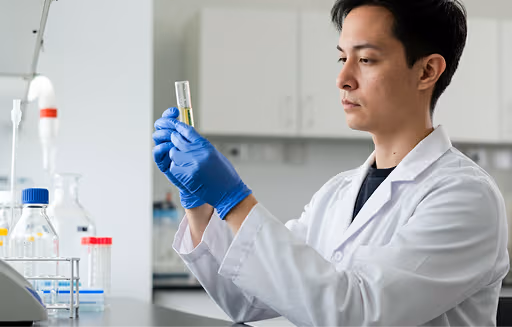 Pharmacist in white coat selecting medication from a shelf filled with medicine bottles and boxes.
