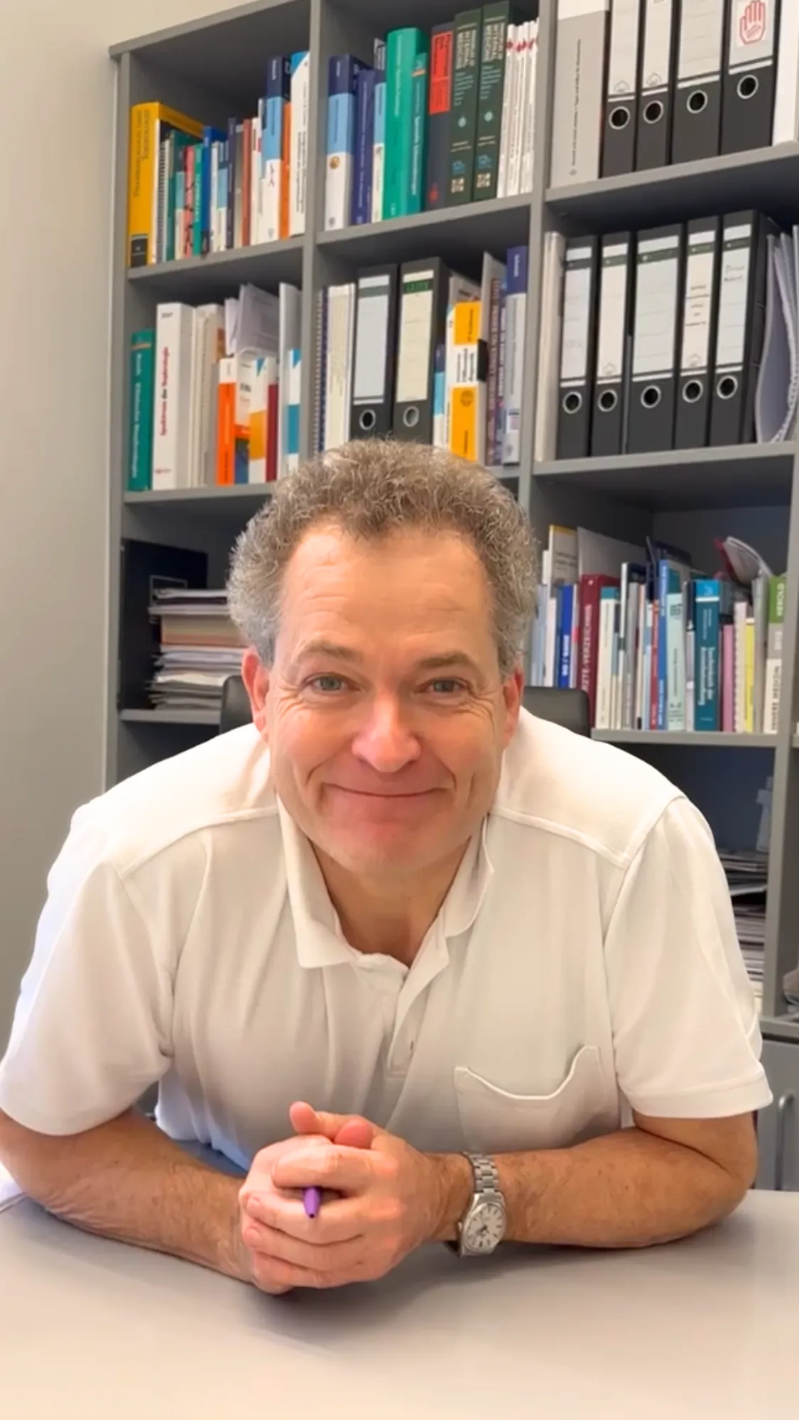 Dr. Frank Lorenz an einem Schreibtisch vor einem vollen Bücherregal.