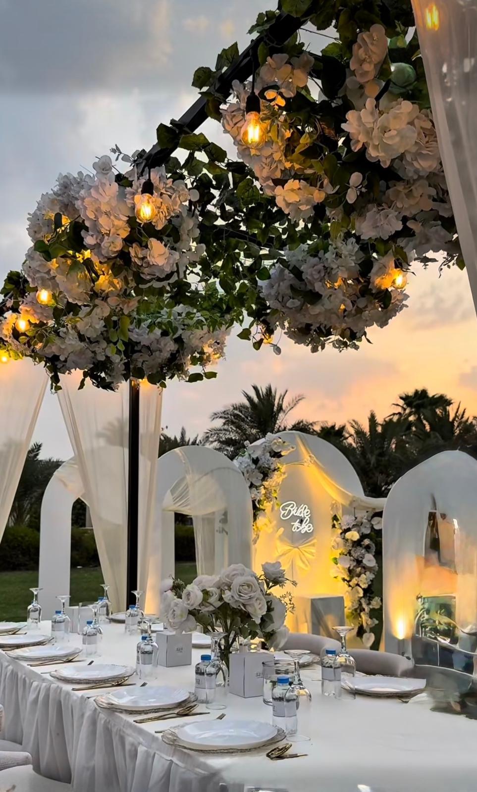 Evening celebration table beneath a floral canopy at sunset
