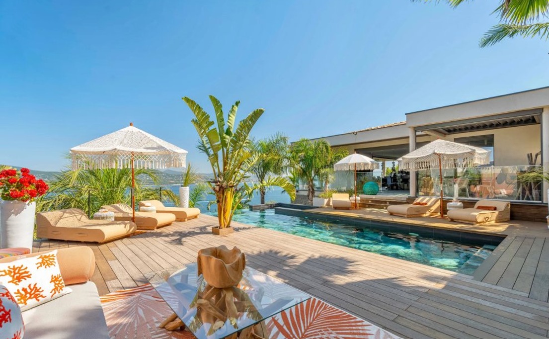 Poolside terrace with parasols and palms overlooking the sea in Saint-Tropez