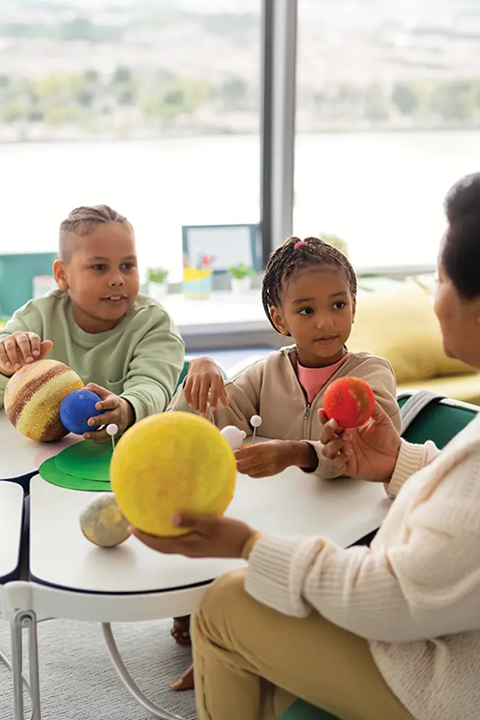 Children and a carer playing together at a table