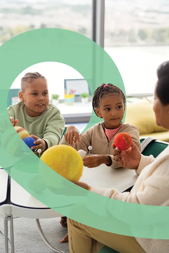 Children and a carer playing together at a table