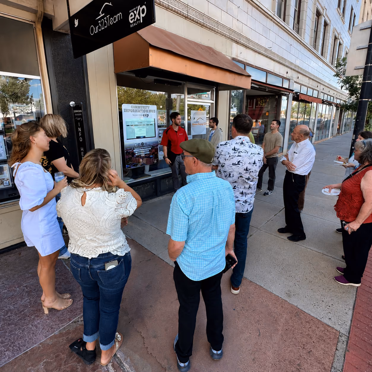 Group of people gathered outside a storefront with Our323Team and eXp Realty signage.