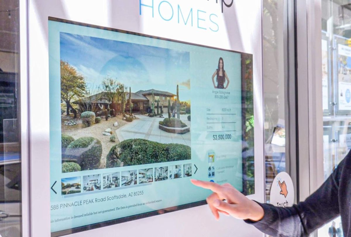 A finger on a WindoVision display, opening a listing through the window glass