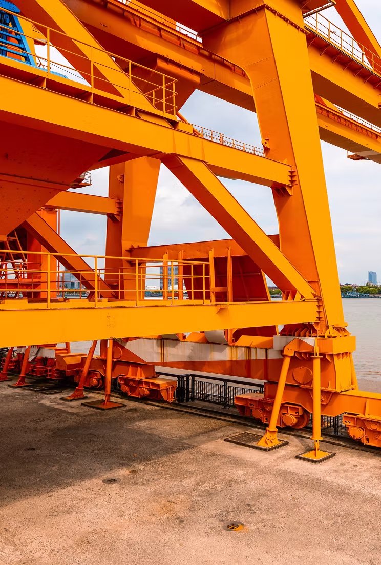 Close-up of large orange industrial crane structure at a waterfront dock.
