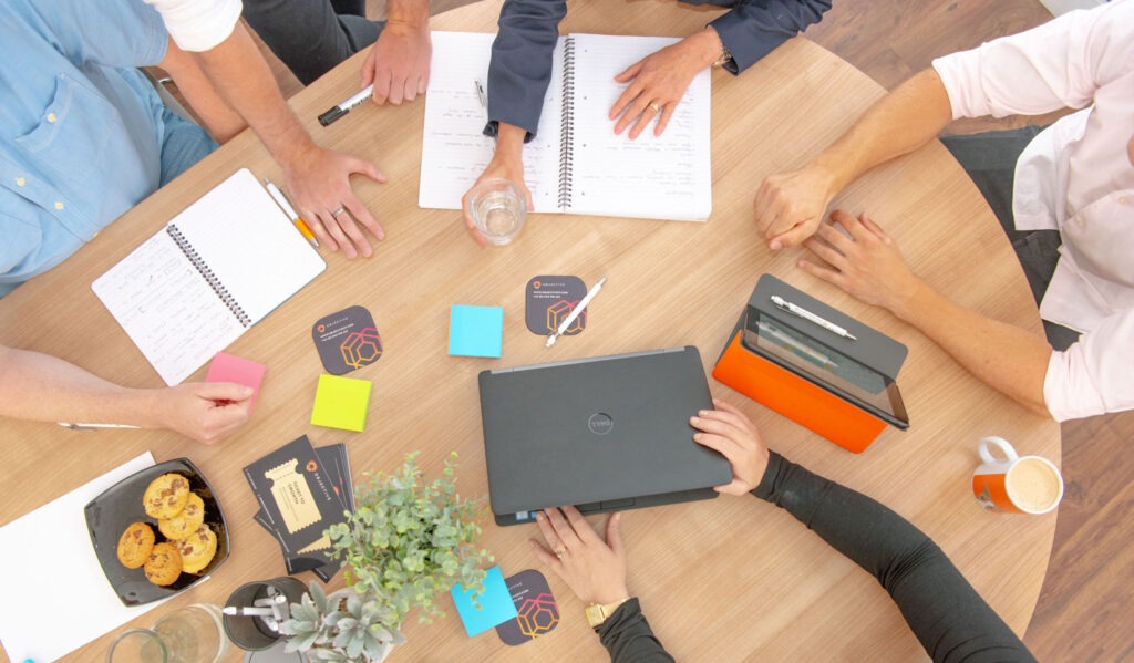 A meeting room table with Laptop, iPad and Notepad from above