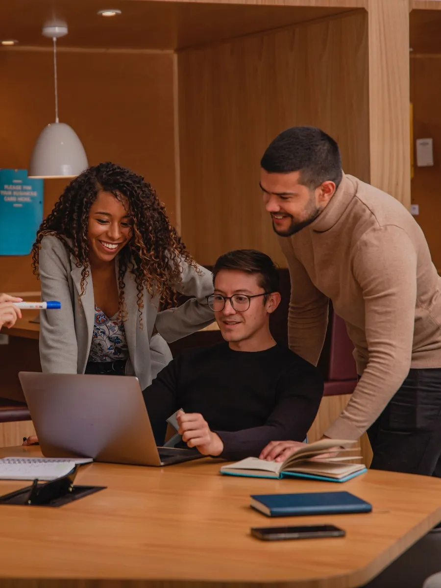 Three people discussing something while looking at a laptop.