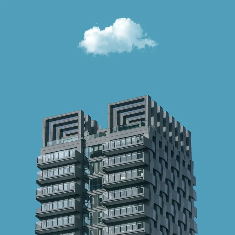 A large building on a sunny clear day with a single cloud floating above it.