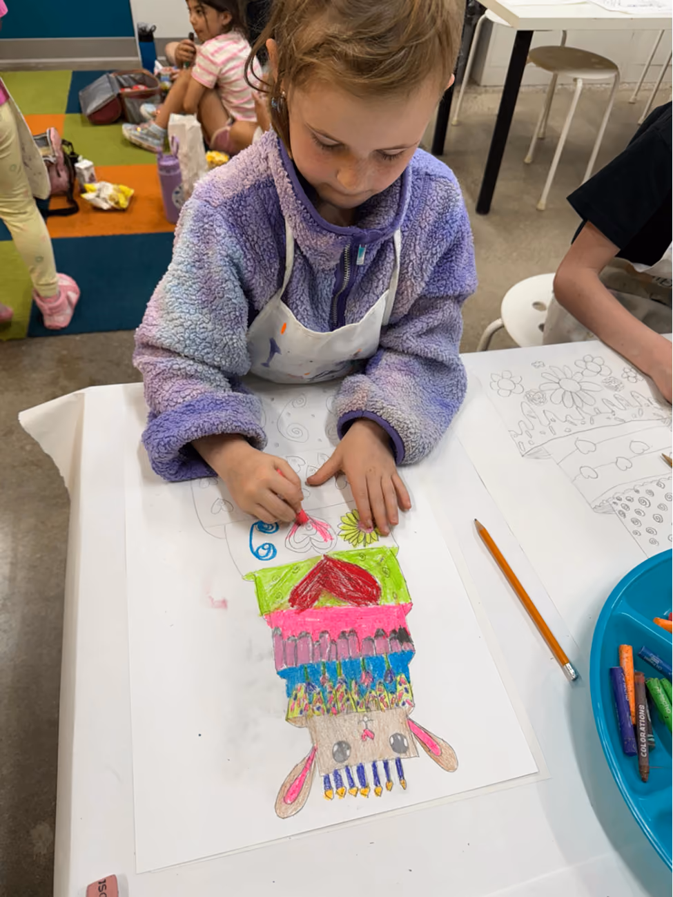 A young child focused on coloring a detailed art project at Kidcreate