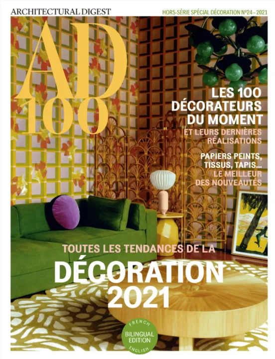 Couverture du hors-série AD 100 d'Architectural Digest 2021, montrant un salon au canapé vert, au paravent en rotin et au papier peint treillage fleuri.