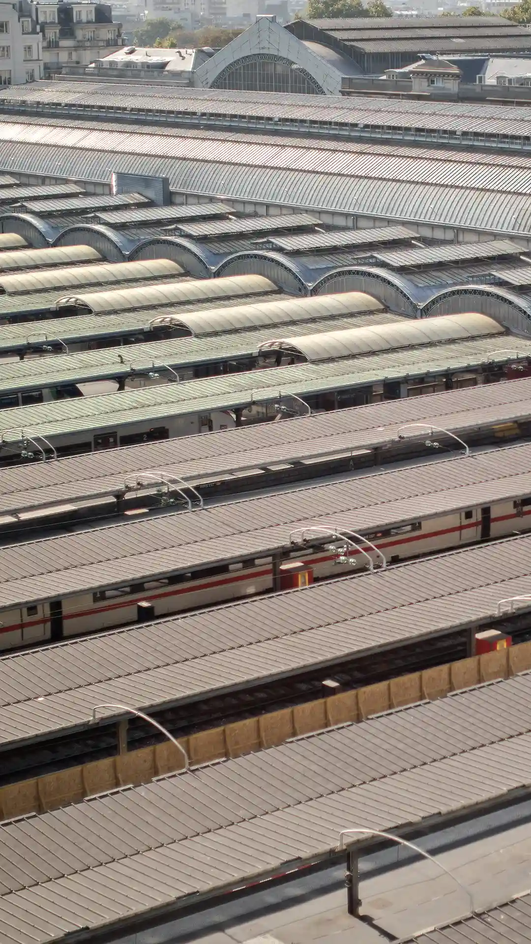 Trains à quai sous les verrières d’une gare, informations pratiques de l’Hôtel Les Deux Gares, Paris 10e