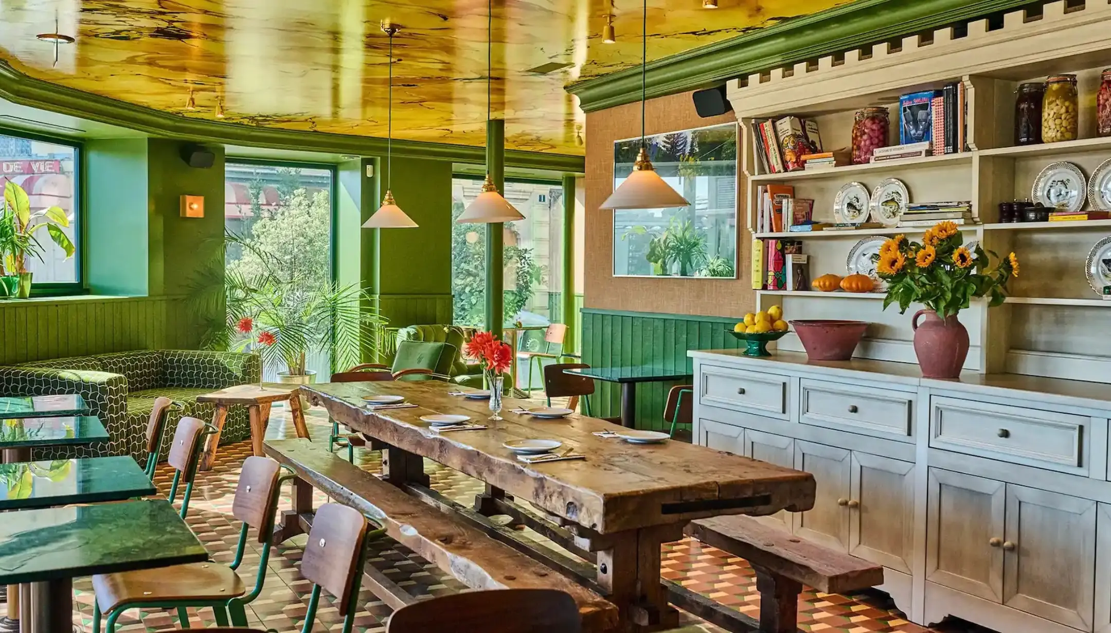 Salle aux murs verts et grande table en bois dressée du Café Les Deux Gares, restaurant néo-bistrot à Paris 10e