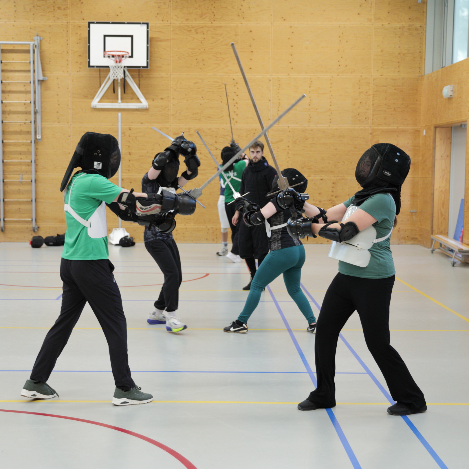 Oefening tijdens een bedrijfsuitje zwaardvechten. Deelnemers voeren een oefening uit terwijl instructeur Xander Bruins met hen meekijkt.