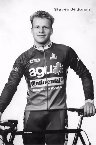 Cyclist Steven de Jongh in racing outfit holding a bike, black and white studio portrait.