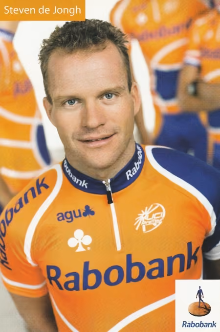 Cyclist Steven de Jongh in an orange Rabobank cycling jersey with teammates blurred in background.