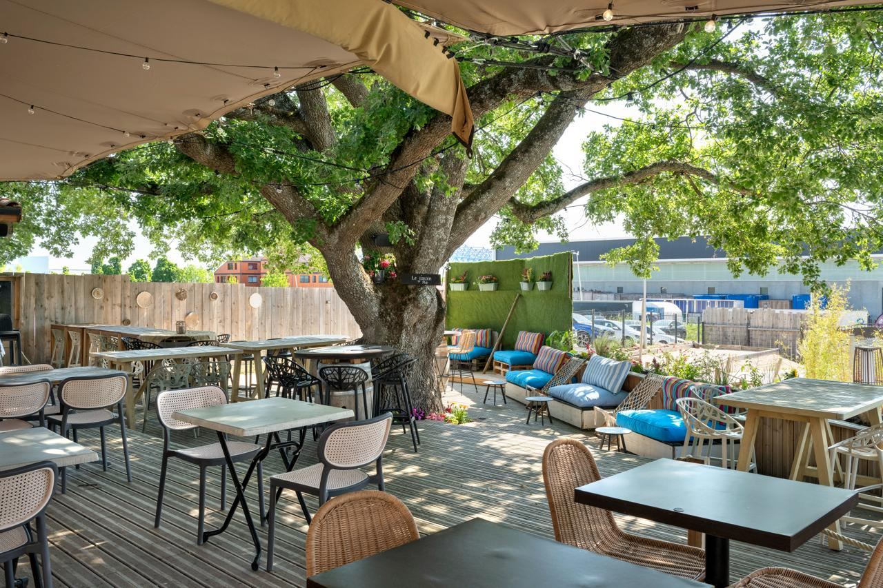Aménagement du bar-restaurant La Ville en Rose, terrasse ombragée sous les arbres, par Imagine Conception
