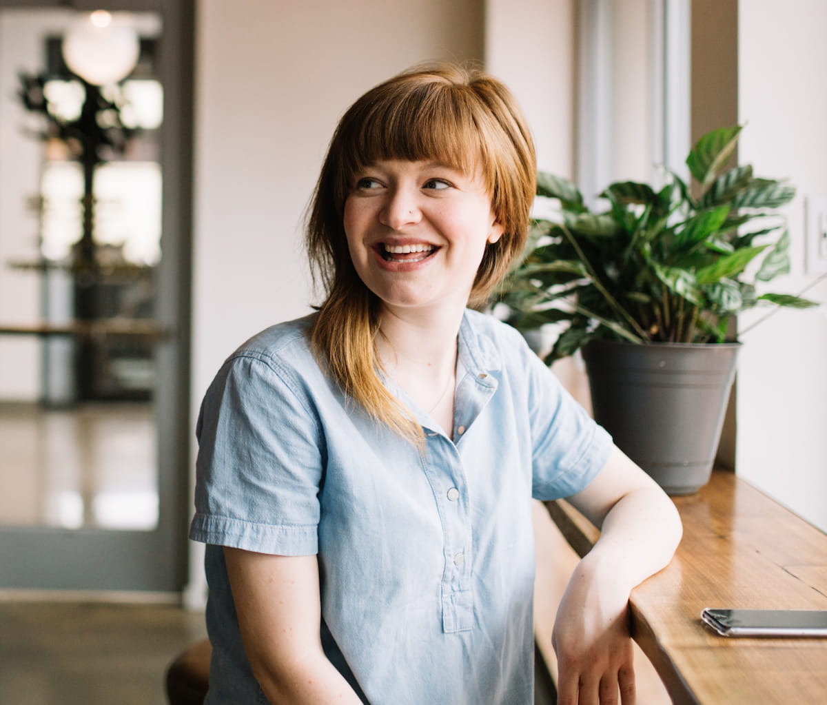 Smiling woman sat down in a communal meeting area