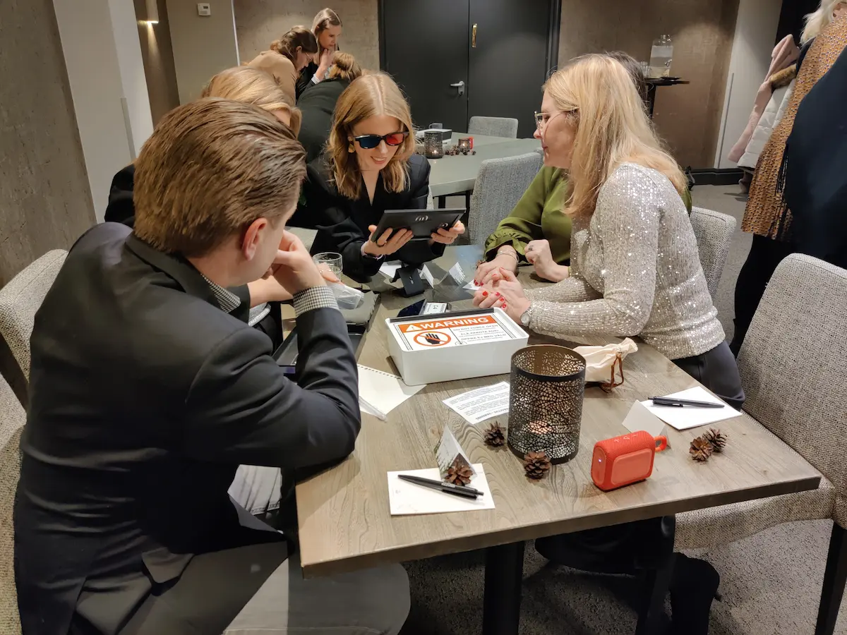 Osallistujat pelaamassa tiimiaktiviteettia pöydän ääressä