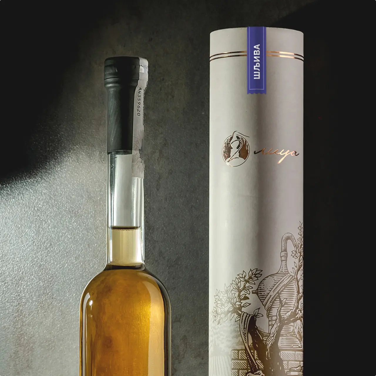 Tall glass bottle with amber liquid next to a white cylindrical box with gold and blue detailing with the dva lica logo.