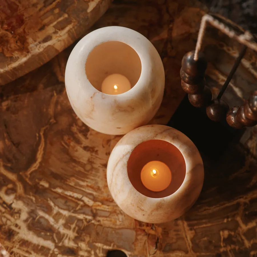 Brandende onyx waxinehouders op een blad van versteend hout