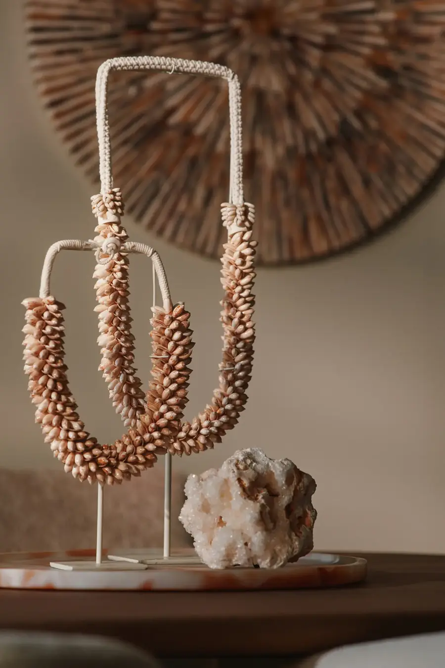 Schelpenketting op standaard naast een stuk ruw kwarts
