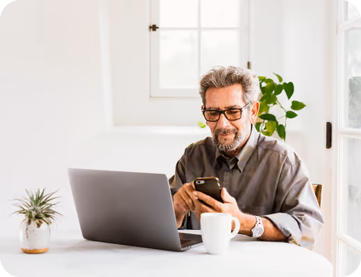 Man using mobile banking app on phone and laptop