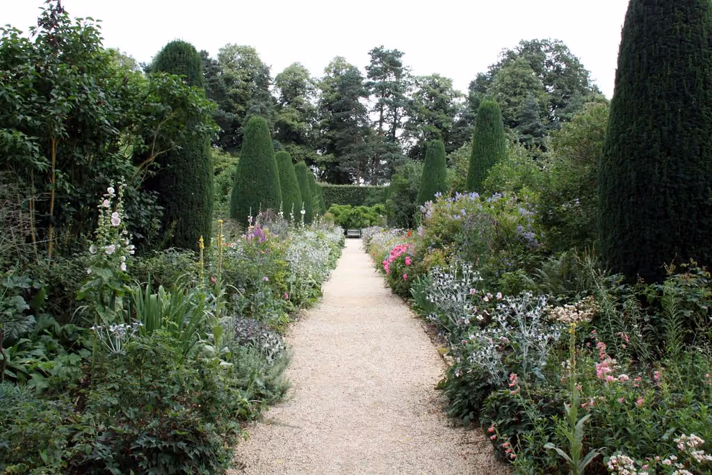 A colourful garden in full bloom with a grass path