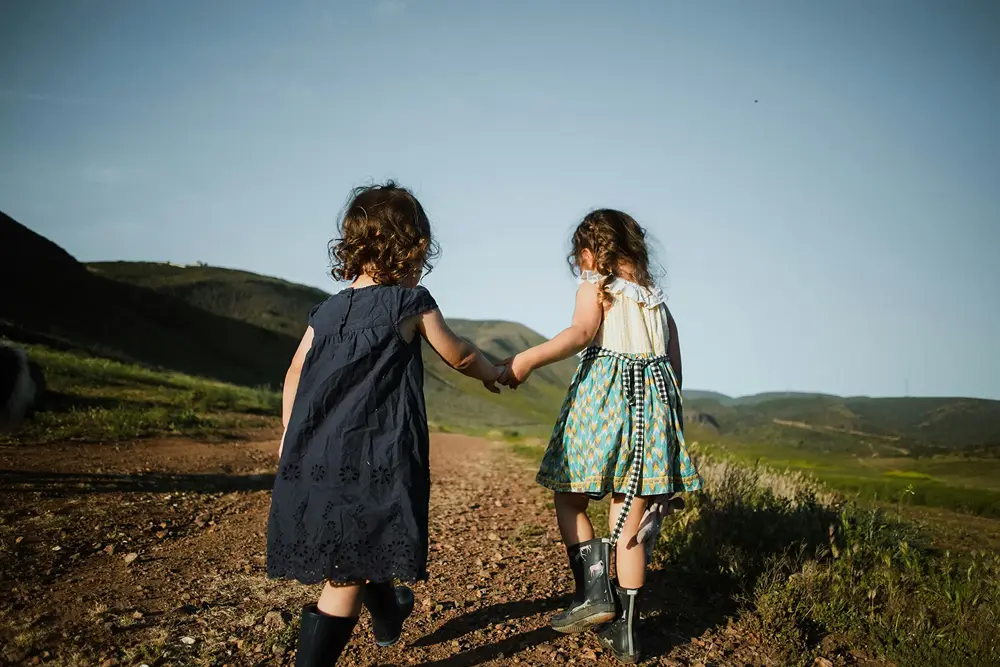 Two children walking away hand in hand along a hillside path, stock image