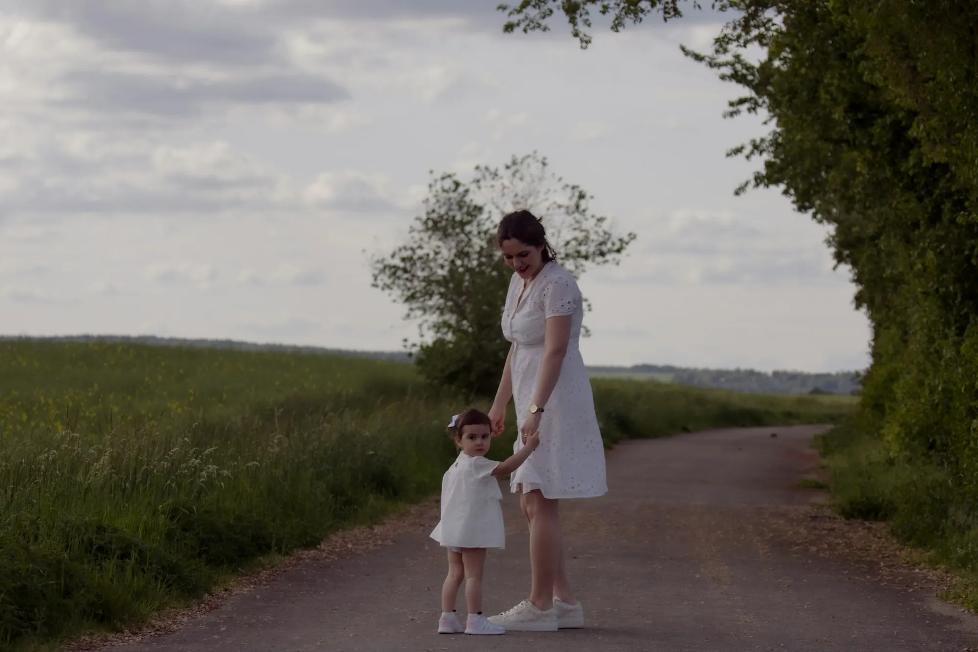 Adult and young child walking hand in hand along a country path, stock image