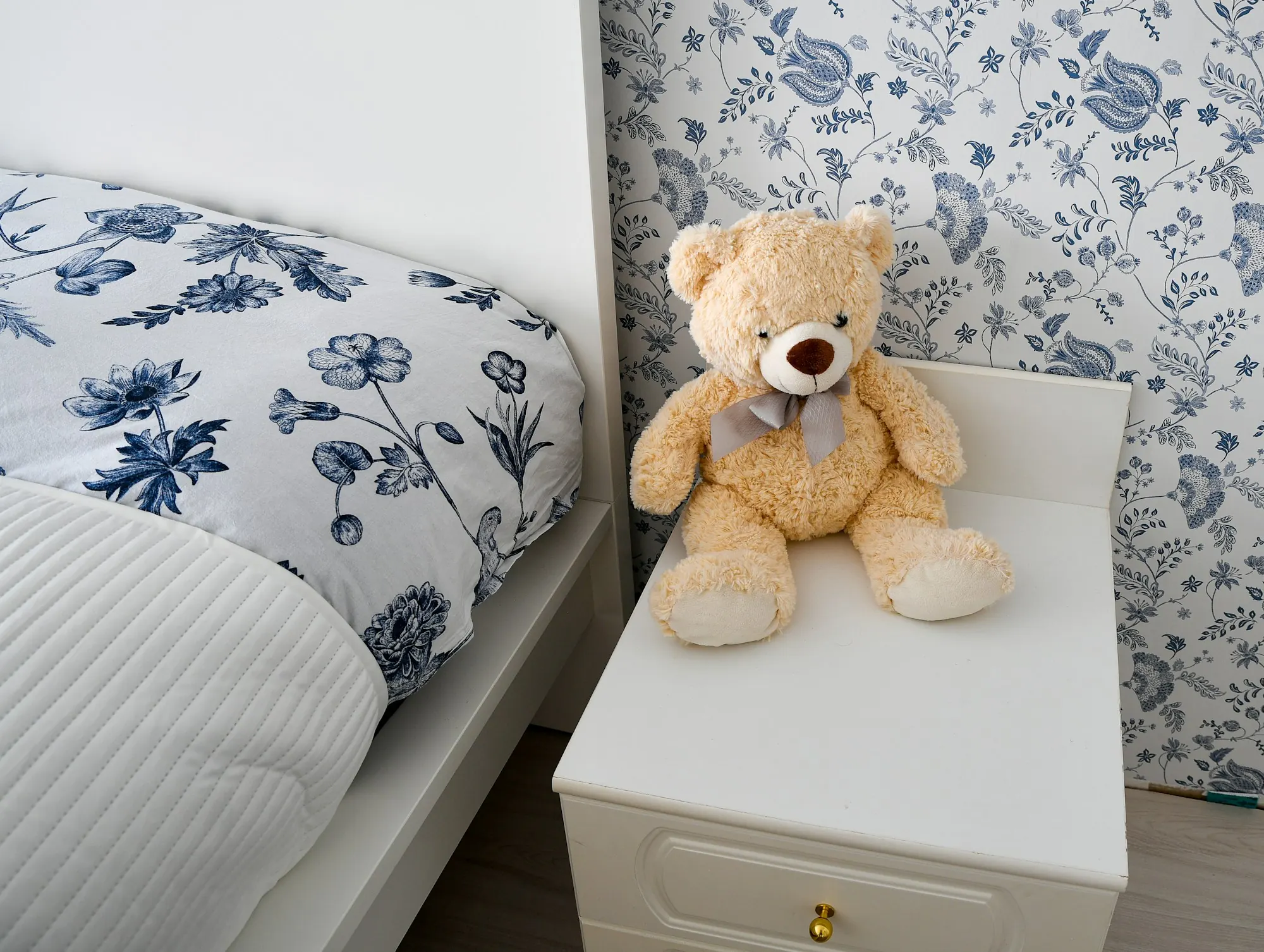 Teddy bear on a bedside table beside a made bed, stock image