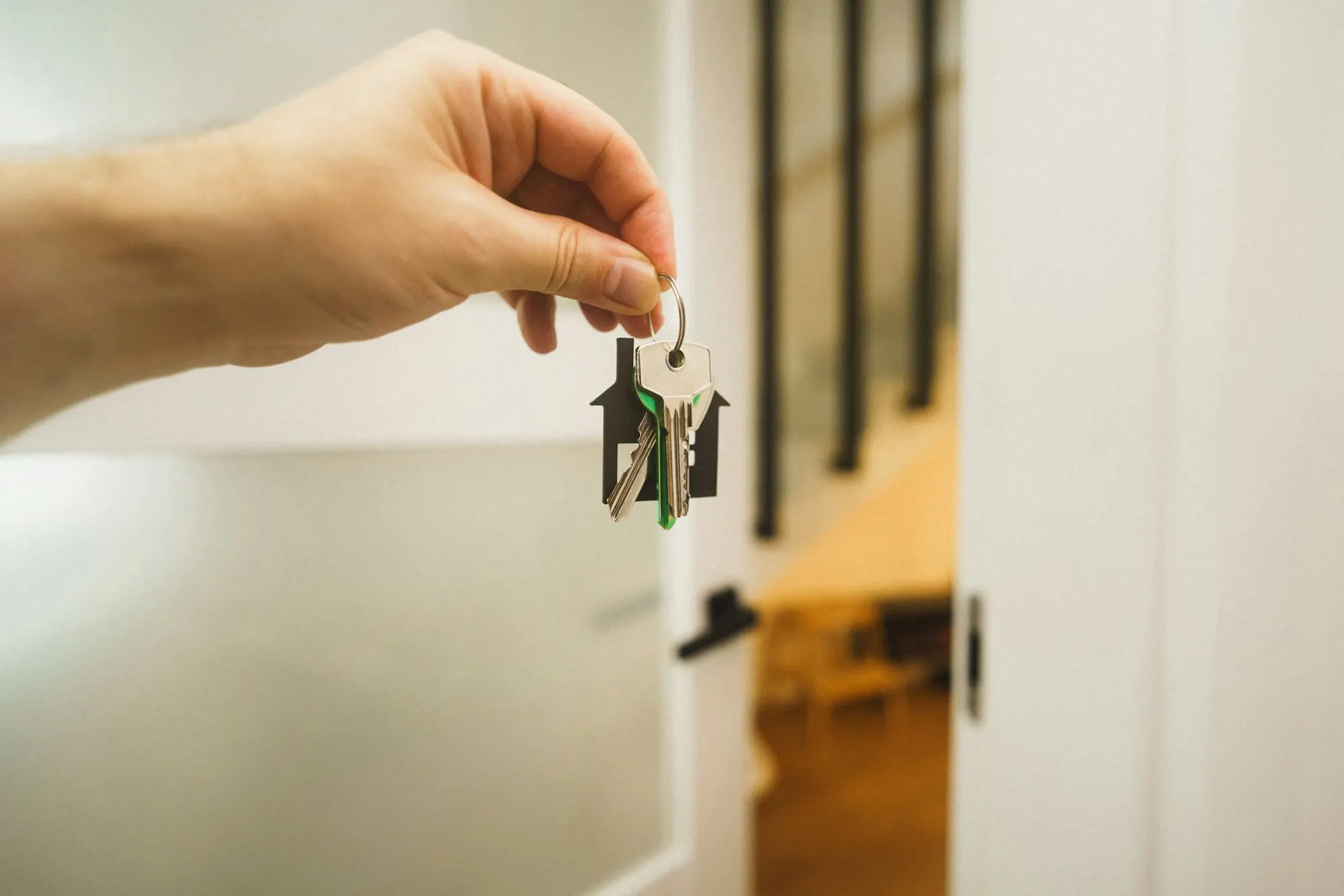 Hand holding out a door key in a hallway, stock image