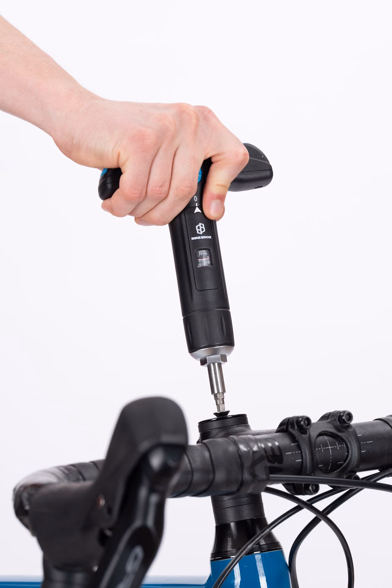 Hand using a torque wrench to tighten the stem bolt on a blue bicycle handlebar.