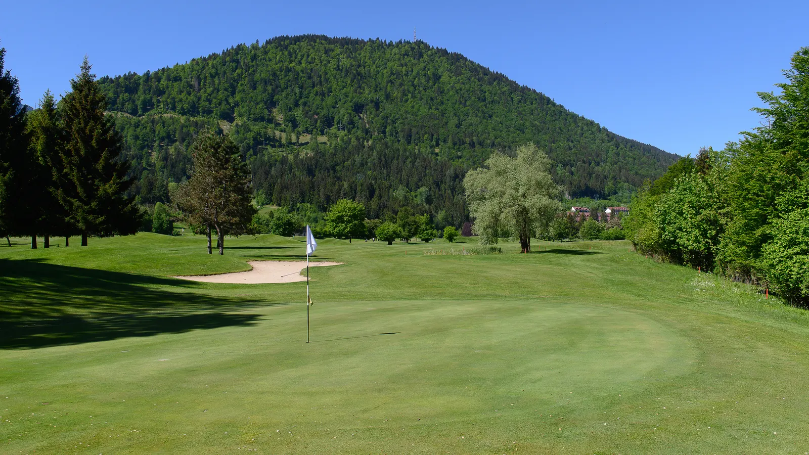Putting Green und Sandbunker vor der Bergkulisse von Tarvisio