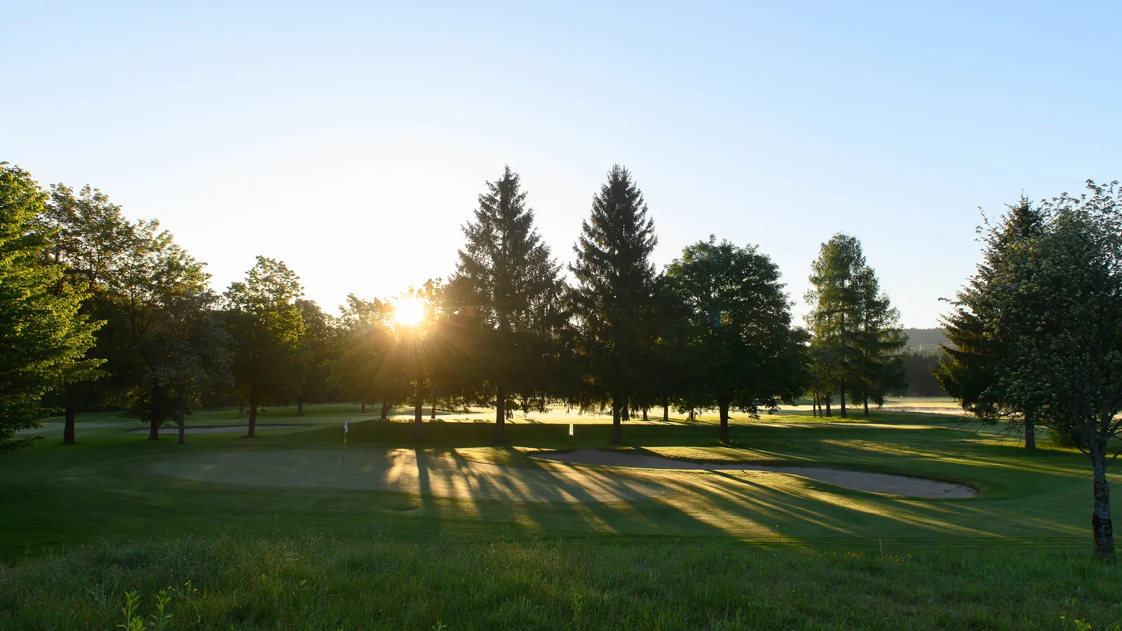 Golfgrün und Sandbunker bei Sonnenaufgang in Tarvisio