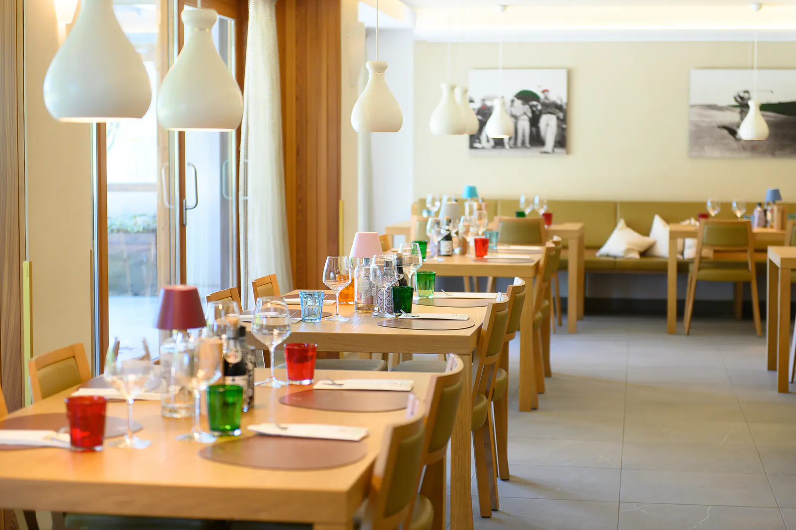 Gedeckte Restauranttische mit farbigen Gläsern und moderner Beleuchtung