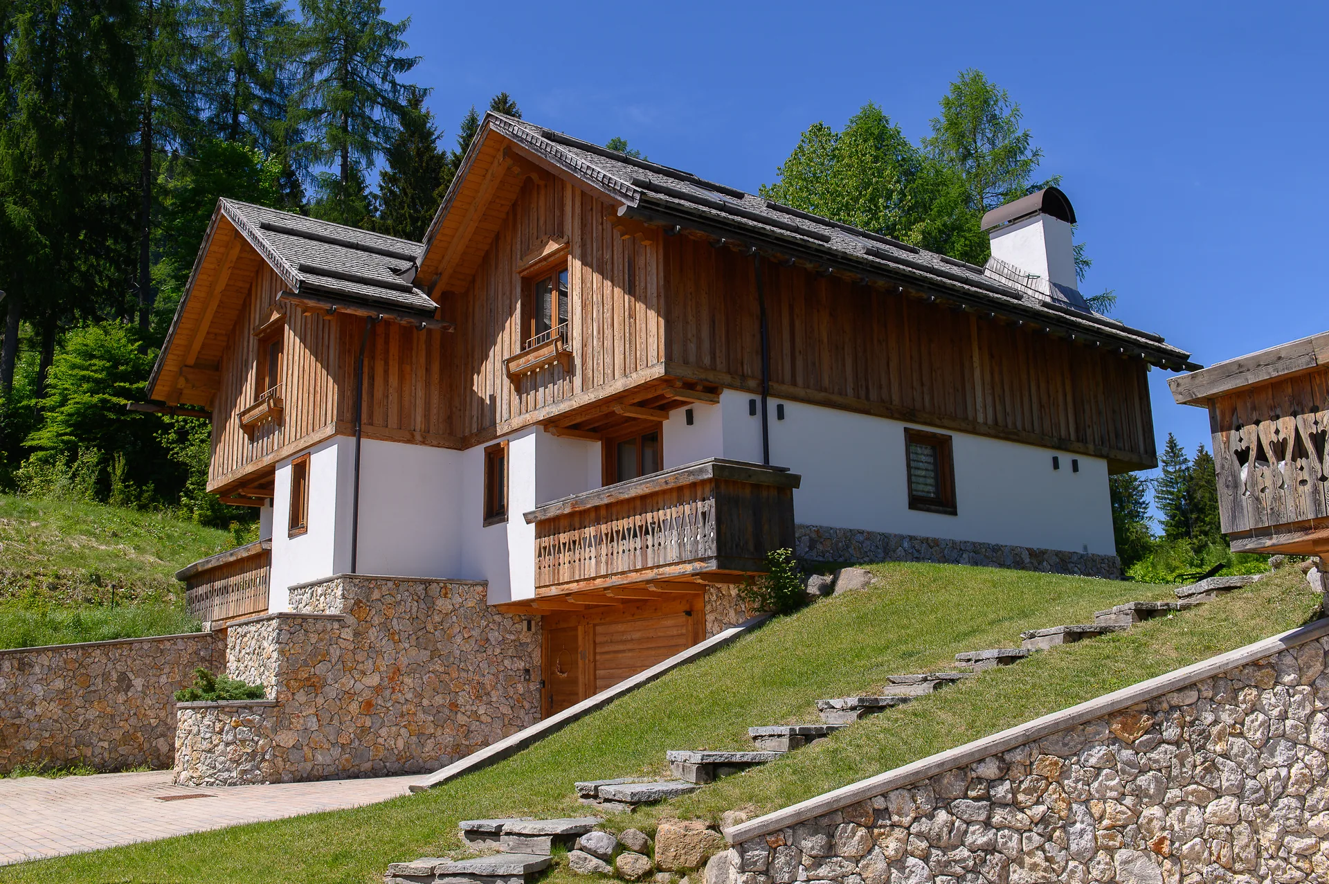 Seitenansicht eines hochwertigen Golf-Chalets in alpiner Architektur
