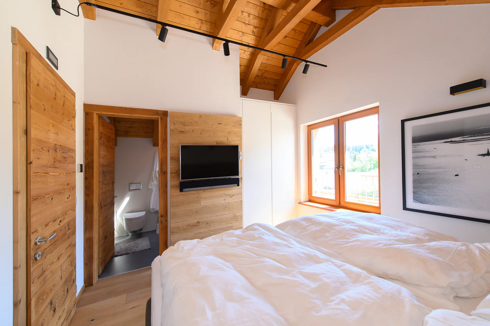 Schlafzimmer mit sichtbarer Holzdecke und modernem Alpendesign