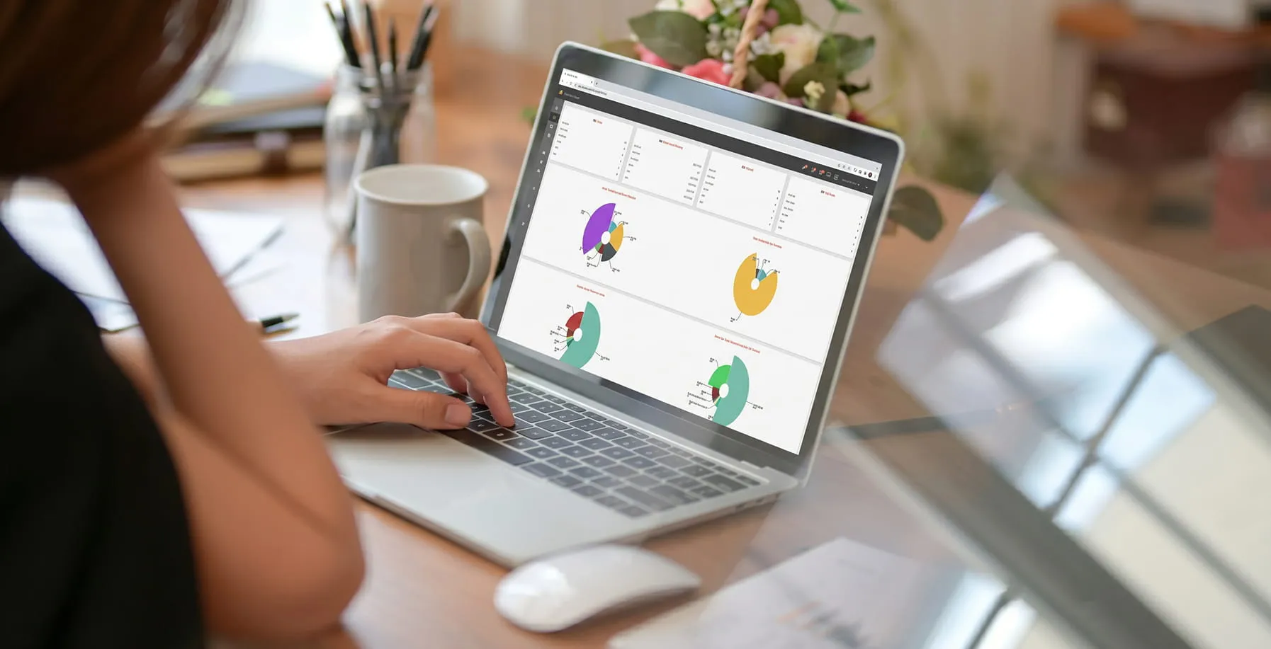 Person working on a laptop displaying colorful pie charts and data dashboards on the screen.