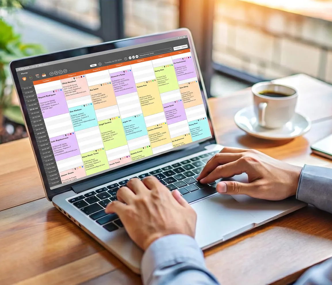 Person typing on a laptop showing a colorful digital appointment schedule or calendar on screen.