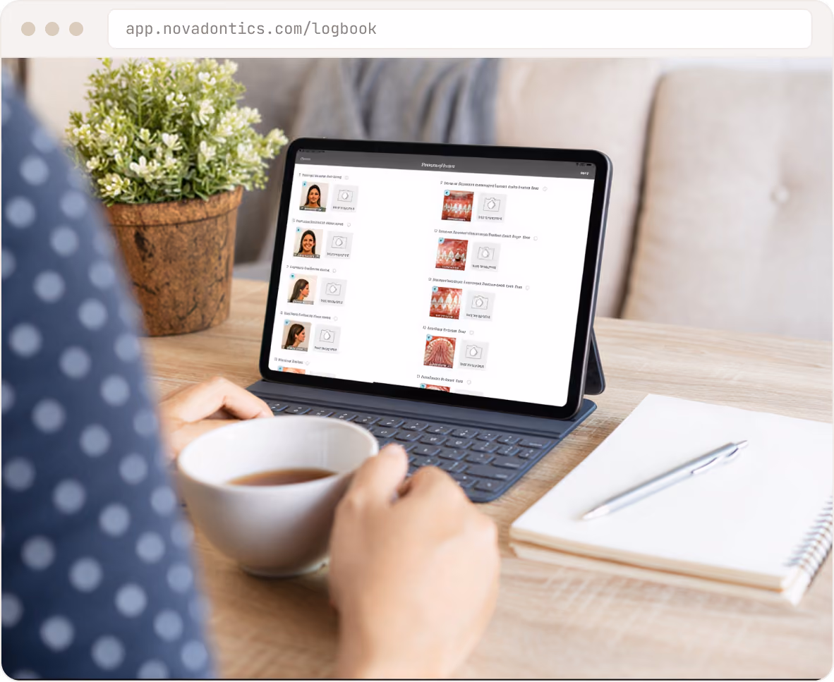 Person holding a cup near a tablet with a dental logbook app open on the screen on a wooden table.
