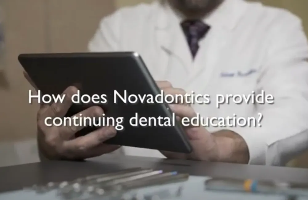 Person in white lab coat holding a tablet with text about Novadontics dental education.