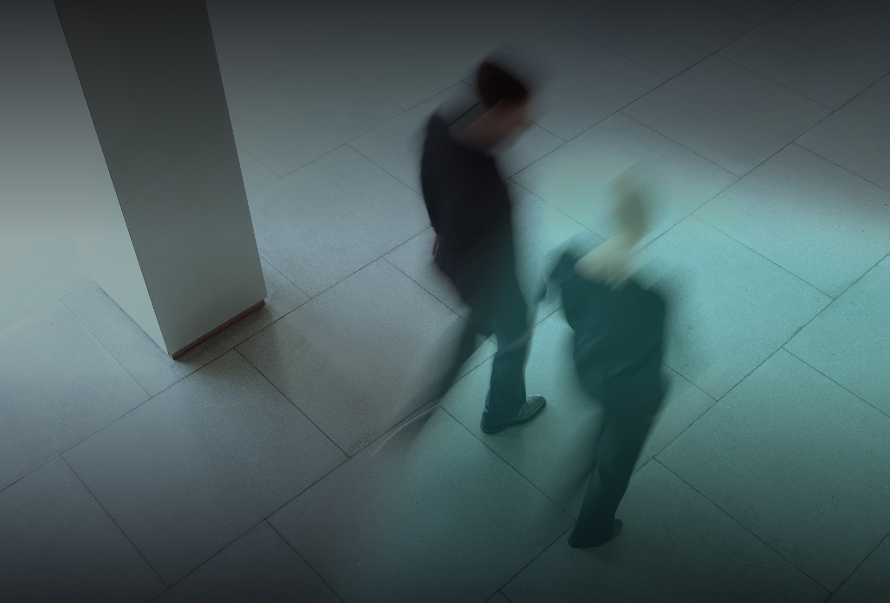 Blurred photograph of two people walking through an office lobby