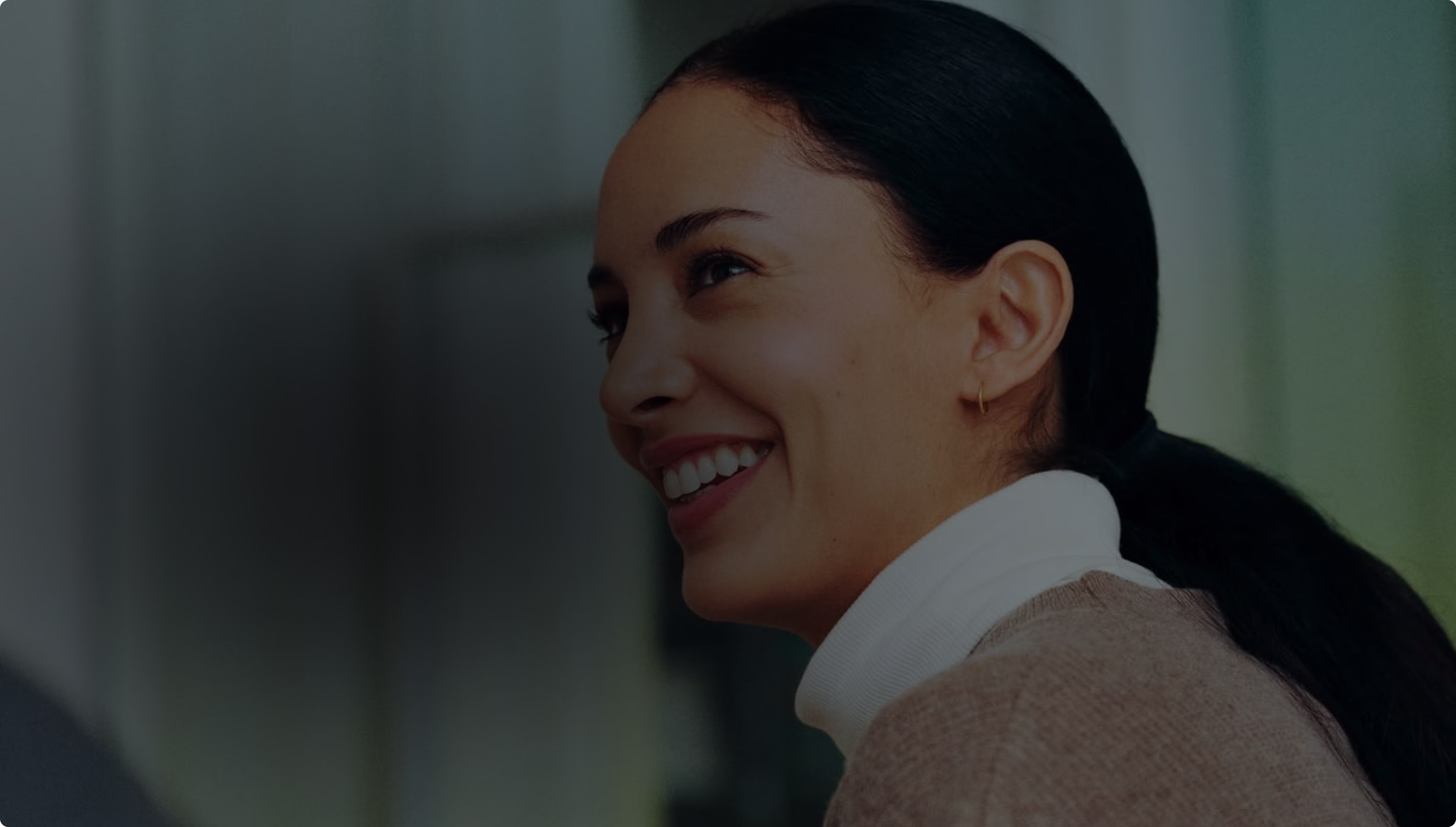 A person smiling and looking away from the camera in an office