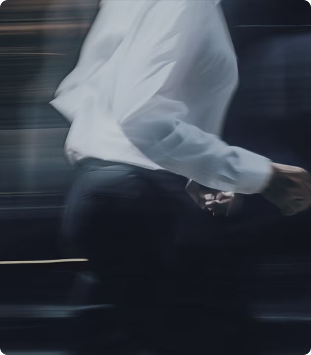 Motion-blurred photo of a person in a white shirt walking through an office