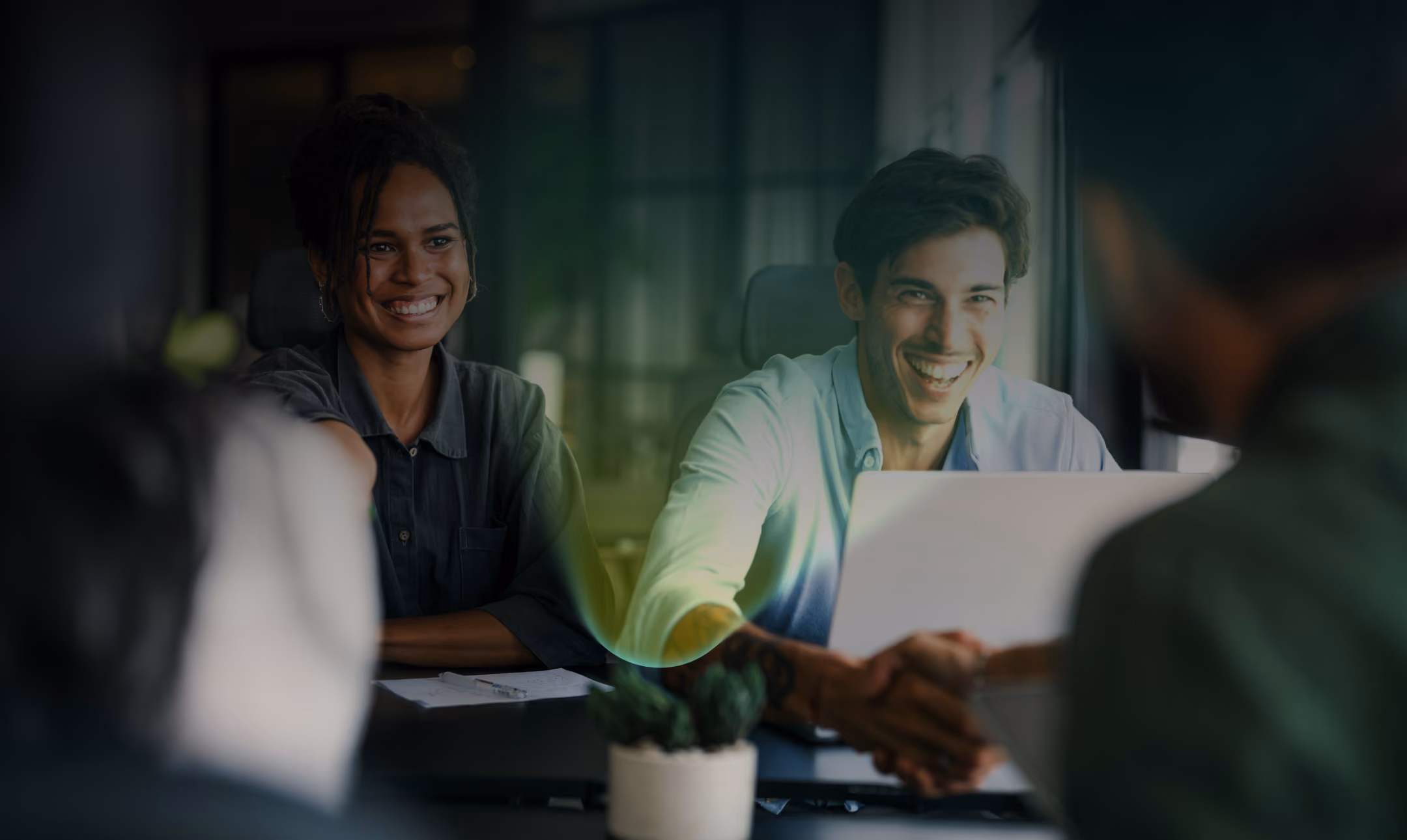Two Pivot colleagues smiling in a meeting while shaking hands across the table