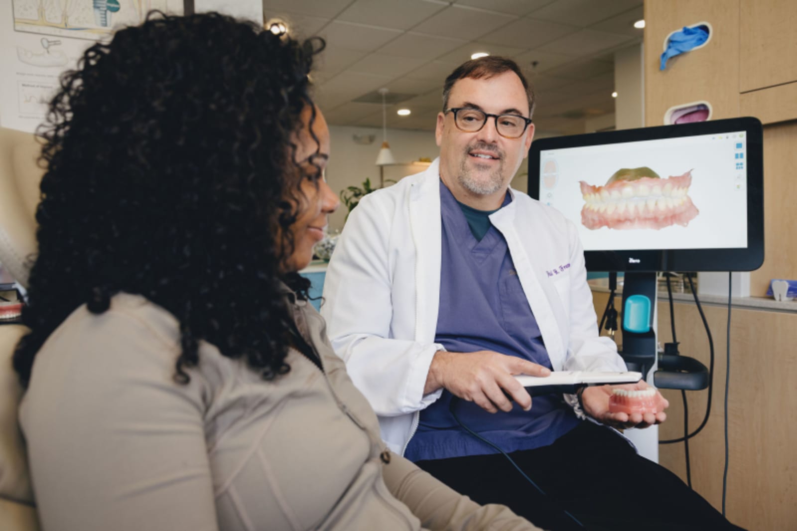 Dentist explaining dental implant procedure to patient using model demonstration