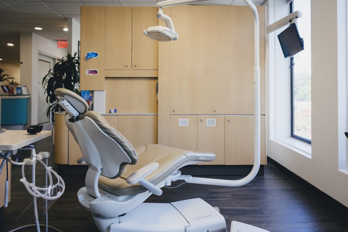 Modern dental treatment room with professional chair, overhead lighting, and clinical equipment