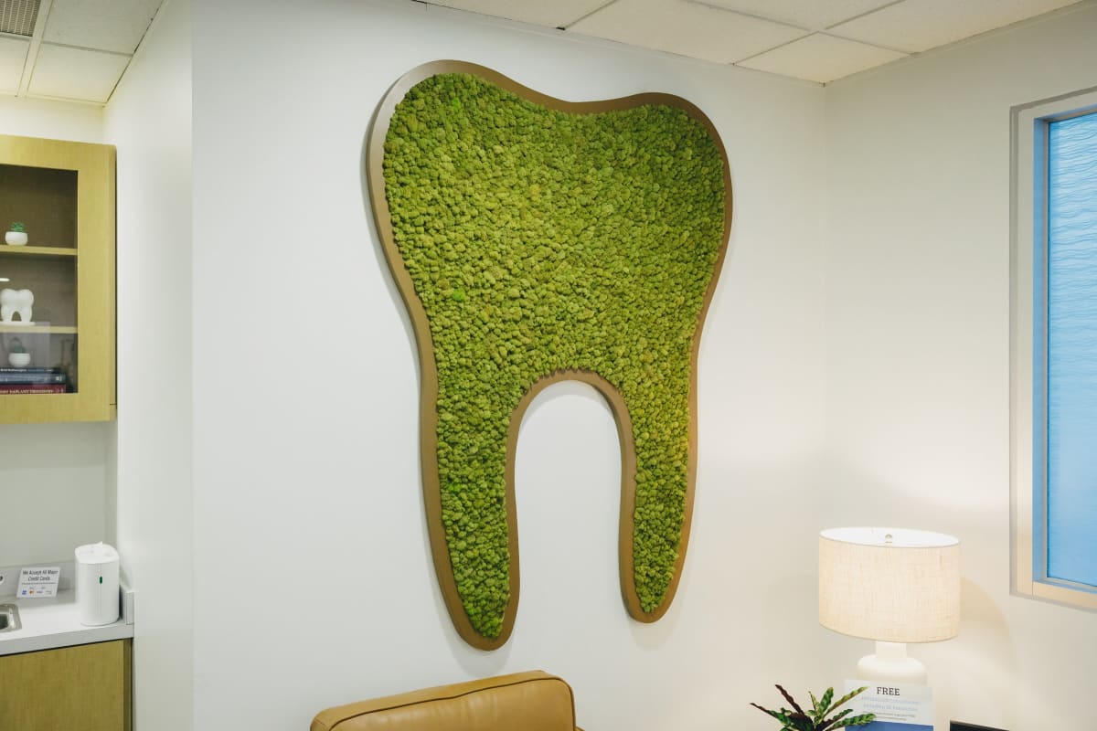 Green moss tooth-shaped art installation symbolizing smile transformation and dental aesthetics